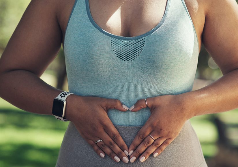 frau-bildet-herz-mit-den-haenden-auf-unterbauch-symbolisiert-lipoedem-ursache-darm
